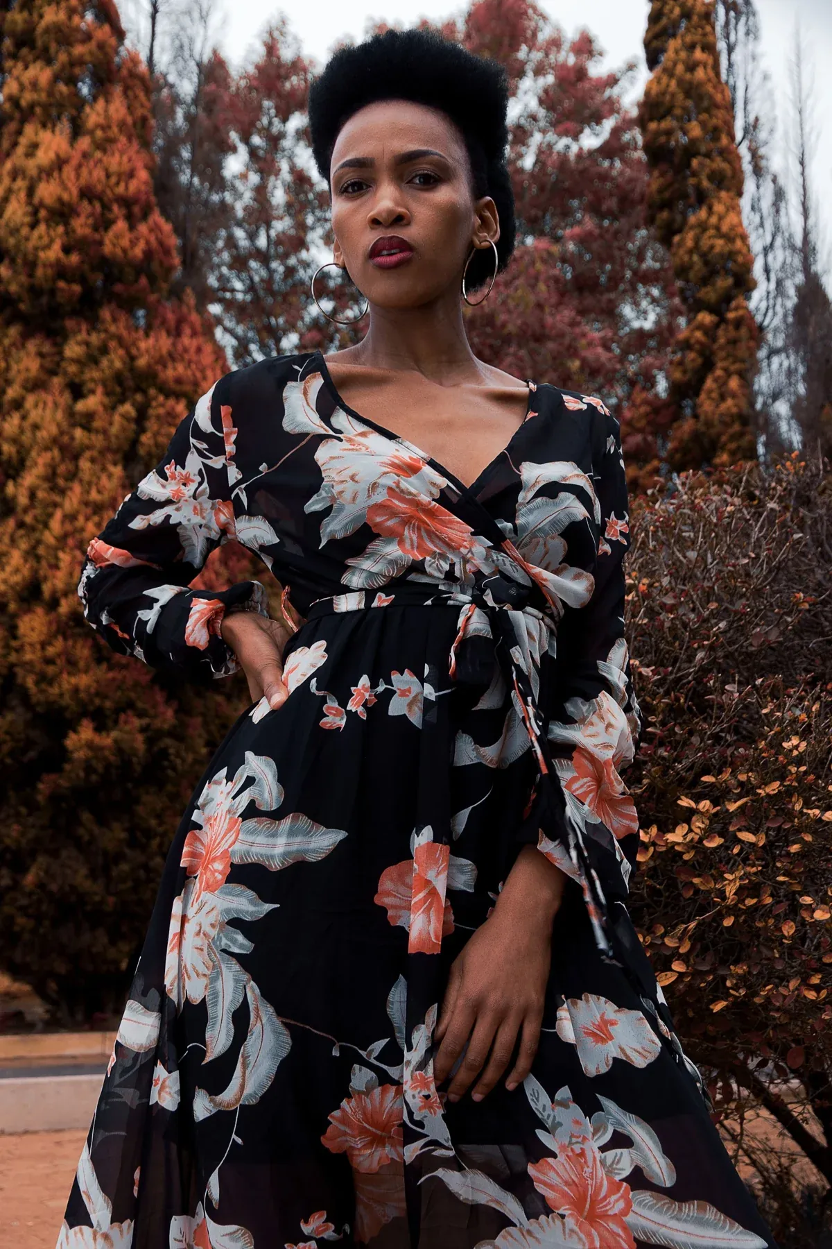 Modelo com vestido de estampado floral sobre fundo preto, fotografada ao ar livre